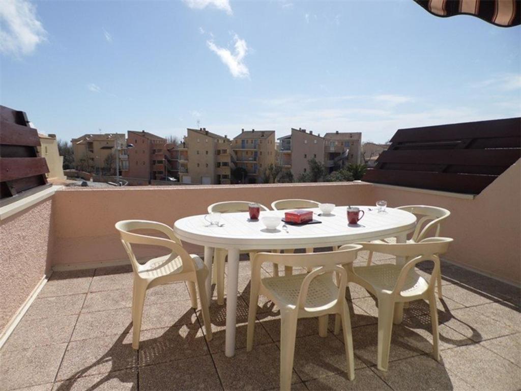 une table blanche et des chaises sur un balcon dans l'établissement Duplex climatisé avec 2 chambres, grande terrasse et parking privé - FR-1-326-611, à Marseillan