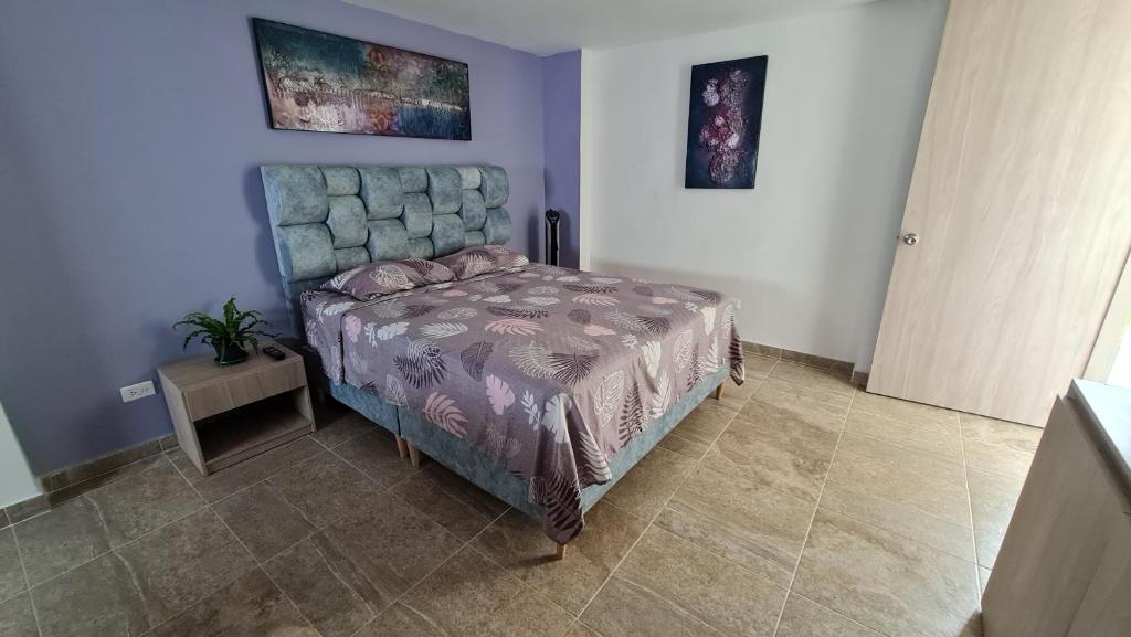 1 dormitorio con 1 cama en una habitación azul en Aparta Estudio Completo - Ibagué - parqueadero para MOTO - Bambú, en Ibagué