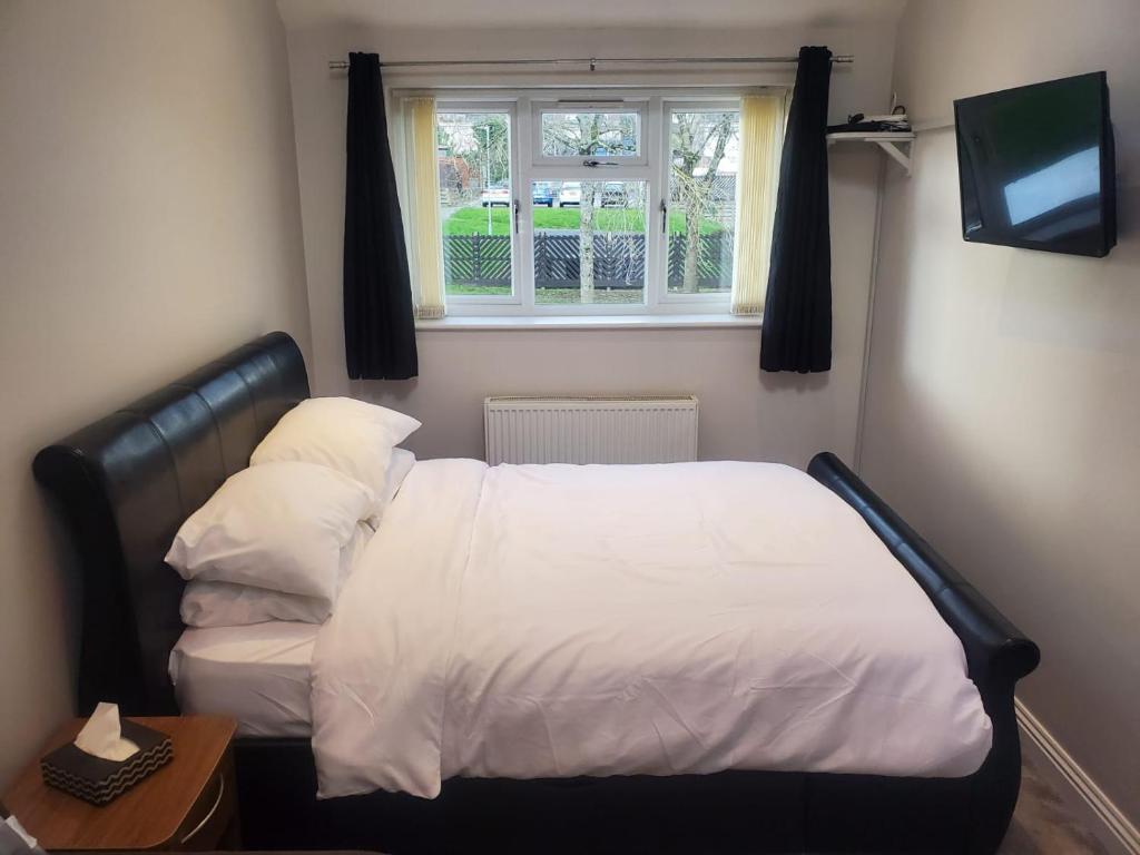 a bedroom with a bed with white sheets and a window at Large Kingsize ensuite in Kingswood, Bristol, BS15 in Kingswood