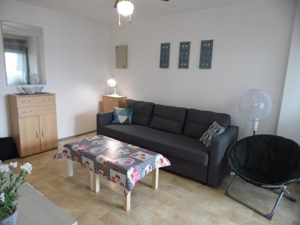 un salon avec un canapé et une table dans l'établissement Appartement cosy à 200m de la plage avec parking privé et loggia, animaux admis - FR-1-326-668, à Marseillan