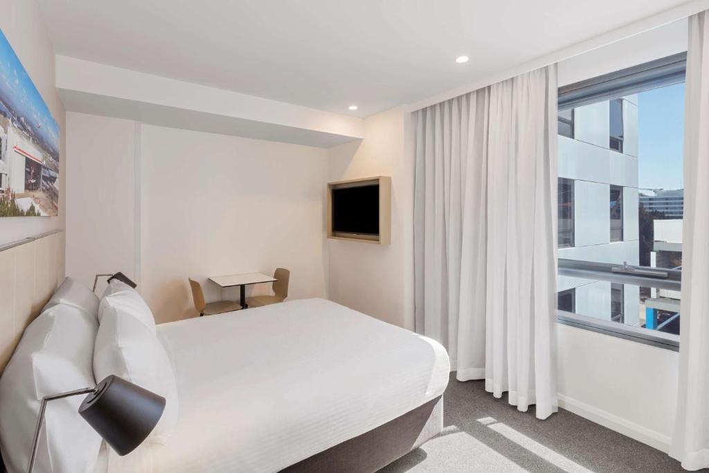a hotel room with a bed and a large window at Travelodge Hotel Sydney Airport in Sydney