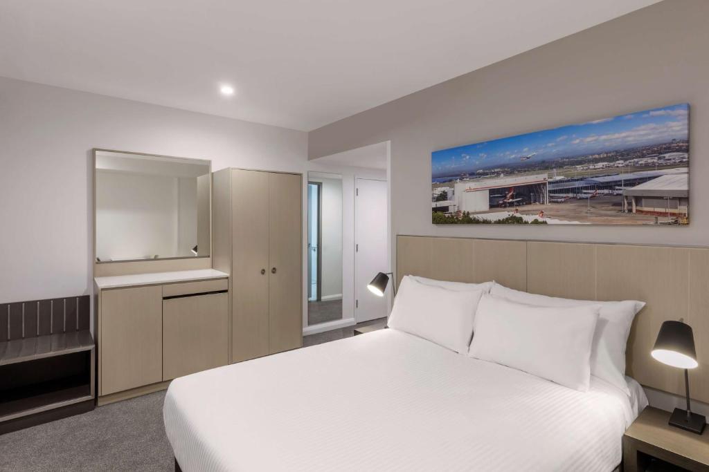 a bedroom with a large white bed and a window at Travelodge Hotel Sydney Airport in Sydney