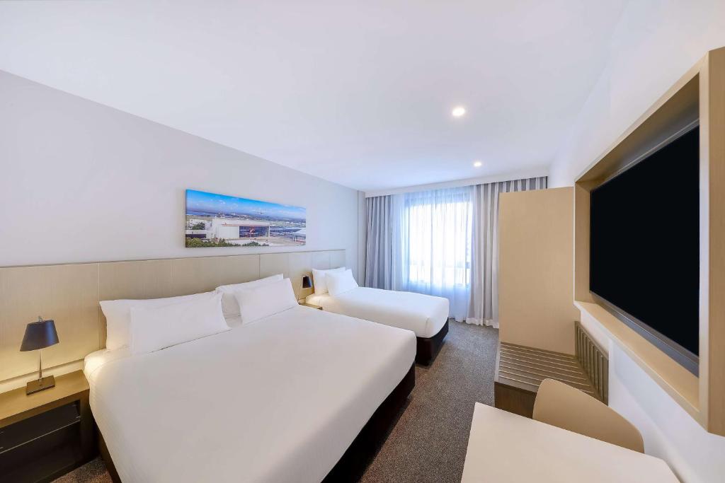 a hotel room with two beds and a flat screen tv at Travelodge Hotel Sydney Airport in Sydney