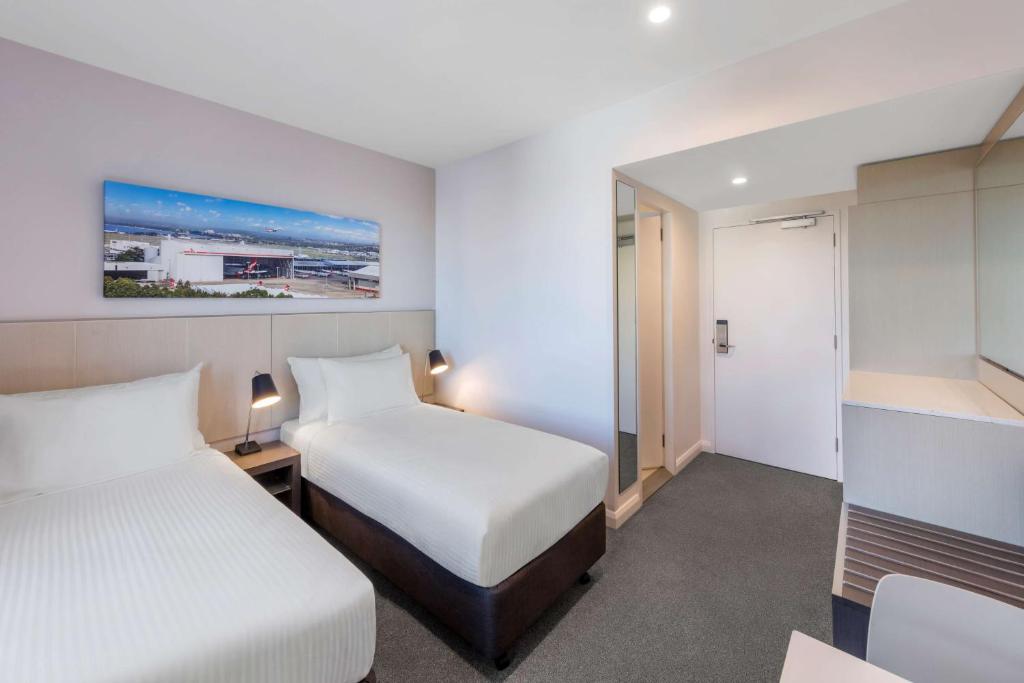 a hotel room with two beds and a bathroom at Travelodge Hotel Sydney Airport in Sydney