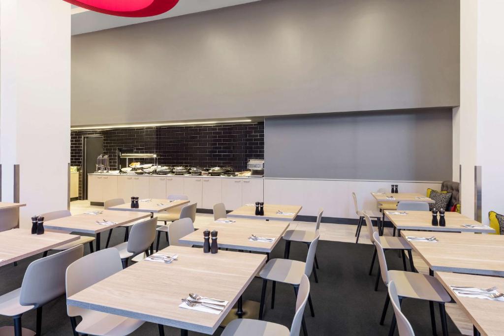 a dining room with tables and chairs and a chalkboard at Travelodge Hotel Sydney Airport in Sydney