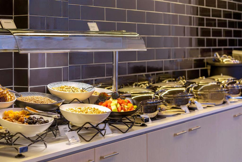 a buffet line with bowls of food on a counter at Travelodge Hotel Sydney Airport in Sydney