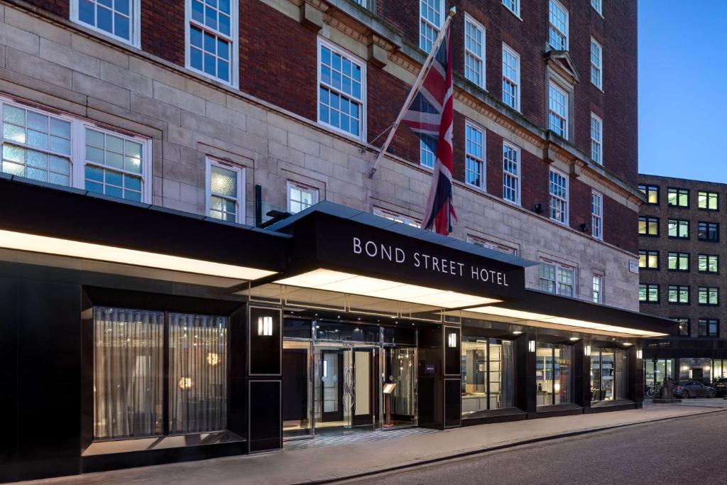 Radisson Blu Edwardian Bond Street Hotel, London في لندن: مبنى عليه لافته مكتوب عليها فندق شارع السند