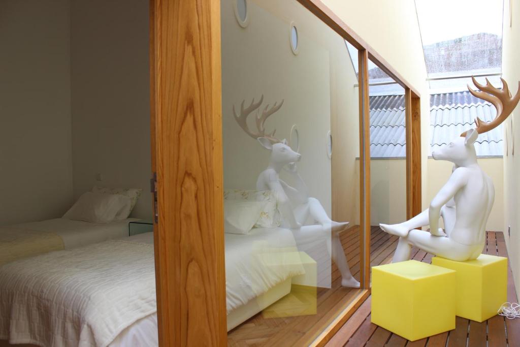 un espejo con dos estatuas de ciervo blanco en un dormitorio en Groove-Wood Loft en Vila Nova de Gaia