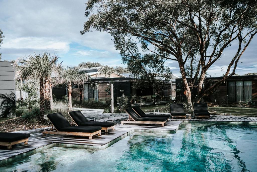 a swimming pool with lounge chairs next to a house at Bangalay Luxury Villas in Shoalhaven Heads