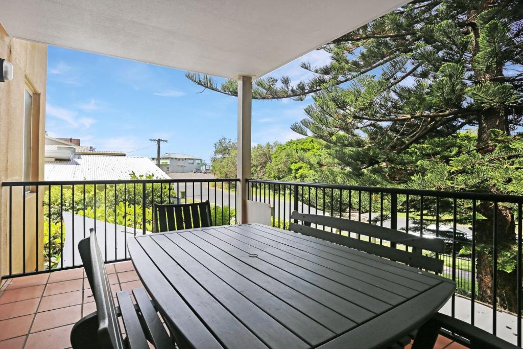 a deck with a table and chairs on a balcony at Aquarius Apartment 4 in Hawks Nest