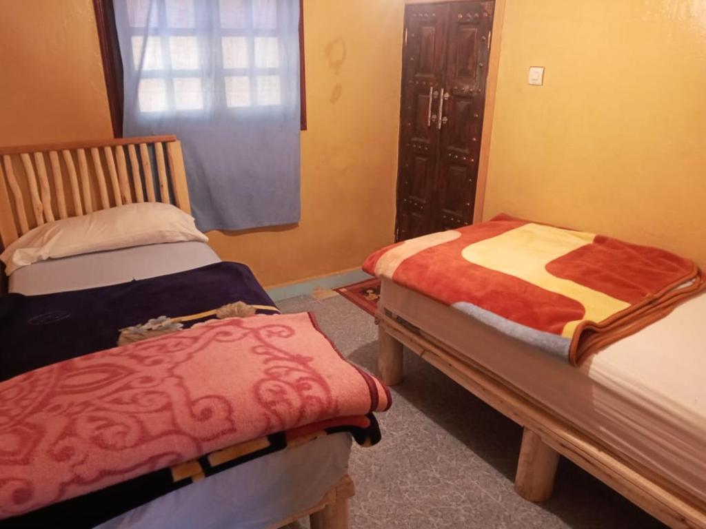 2 Betten in einem Zimmer mit Fenster in der Unterkunft Auberge des lacs in Imilchil