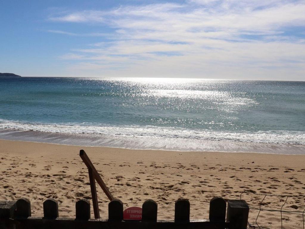 - une plage avec une planche de surf dans le sable et l'océan dans l'établissement Villa de charme en pinède, 4 chambres climatisées, accès direct plage - FR-1-100-209, à Cavalaire-sur-Mer