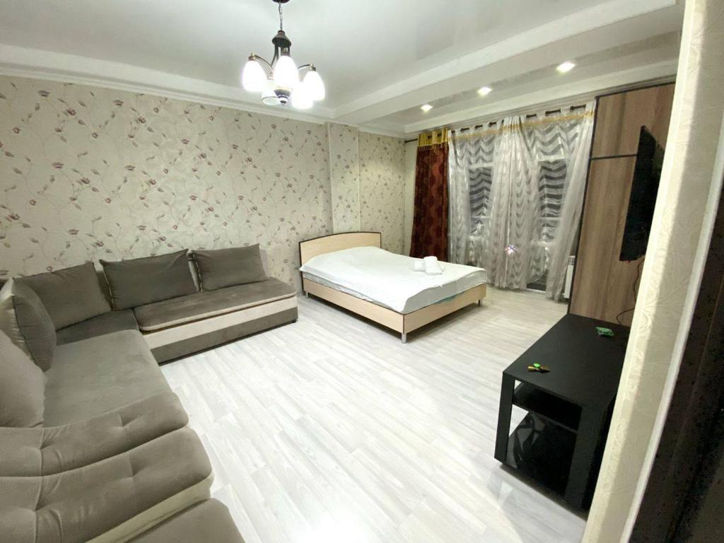 uma sala de estar com um sofá e uma cama em apartment near Cosmopark complex em Bishkek
