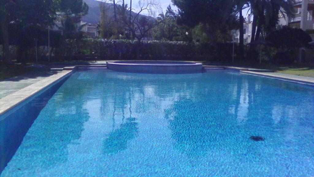 a large swimming pool with blue water in a yard at Apartamento Mare Nostrum in Denia
