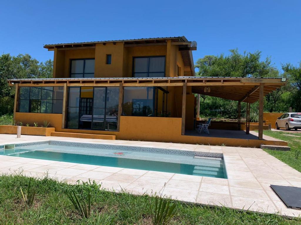 a house with a swimming pool in front of a house at Las Tres Rosas Casa de Campo in Falda del Carmen