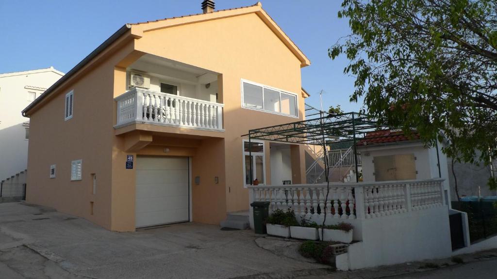 een geel huis met een balkon en een garage bij Apartments with a parking space Grebastica, Sibenik - 13978 in Bašelovići