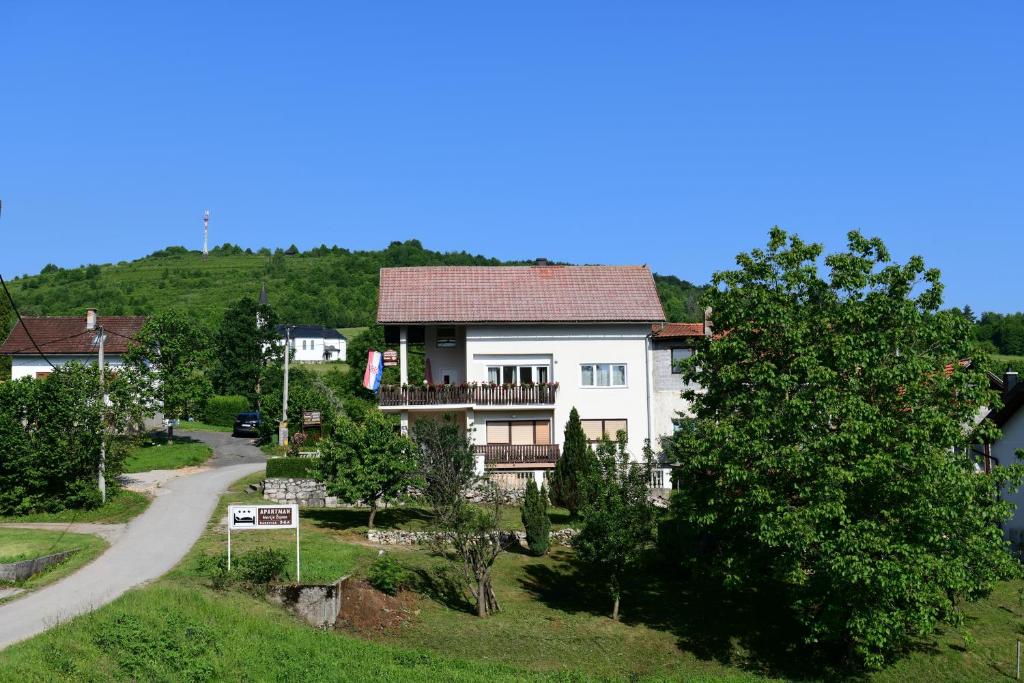 Ein weißes Haus auf einem Hügel neben einer Straße in der Unterkunft Apartments with a parking space Rakovica, Plitvice - 20595 in Rakovica