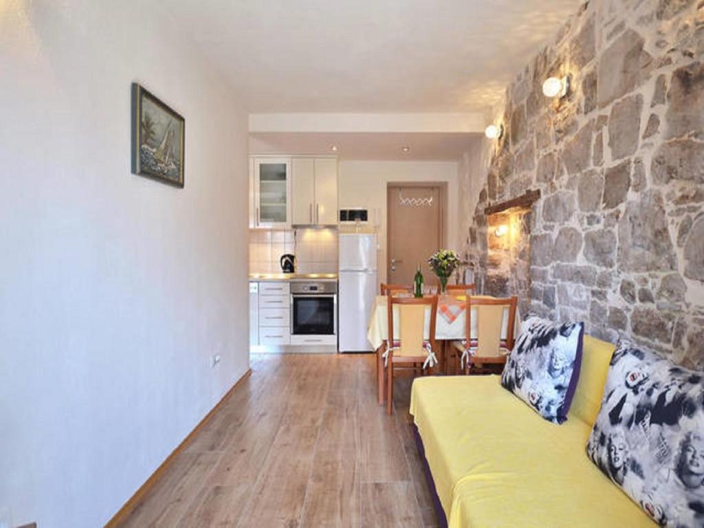 sala de estar con sofá amarillo y pared de piedra en Apartments Nada, en Split