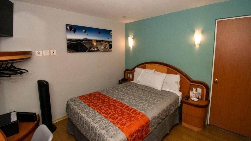 a bedroom with a bed with an orange and gray blanket at Hotel El Conde Naucalpan Only Adults in Mexico City