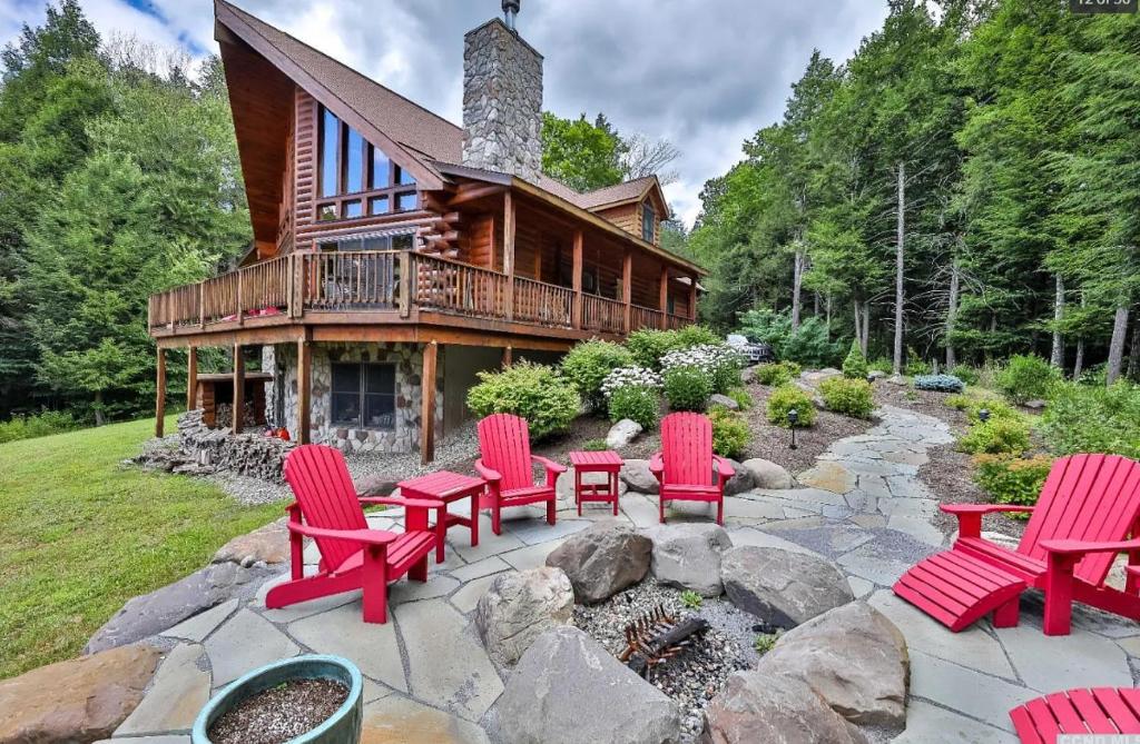 a log house with red chairs and a fire pit at Beautiful Chalet, mins to Hunter/Windham slopes in Jewett