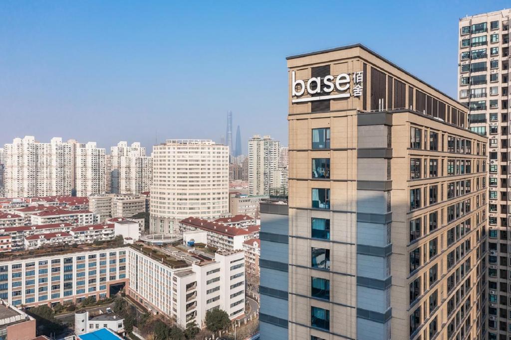 Un grand bâtiment avec un panneau de rose en haut dans l'établissement basePLUS-BINJIANG Serviced Apartment, à Shanghai