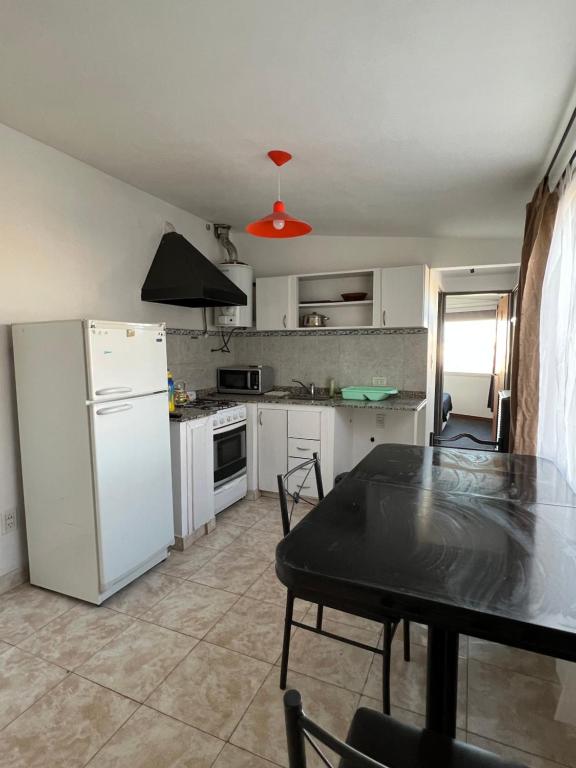 Il comprend une cuisine équipée d'une table et d'un réfrigérateur blanc. dans l'établissement Alojamiento ruta 3, à Trelew