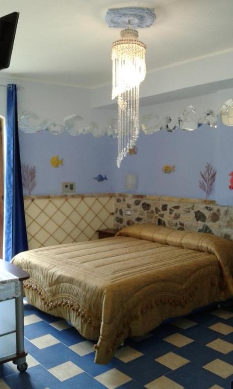 Un dormitorio con una cama grande y una lámpara de araña. en Olimpo Palace Affittacamere, en Scilla