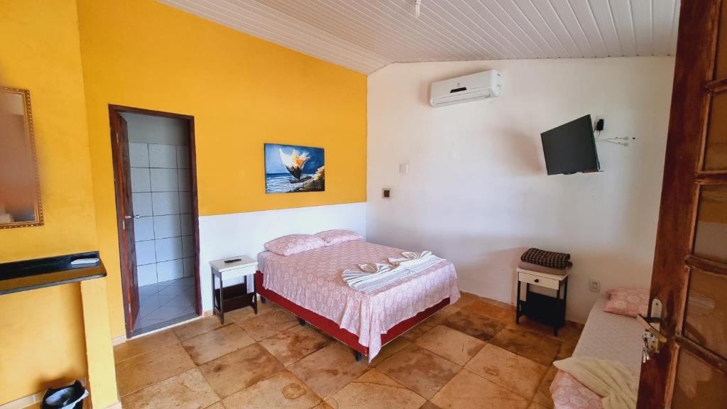 a bedroom with a bed and a tv on the wall at Suites em Canoa Quebrada in Aracati