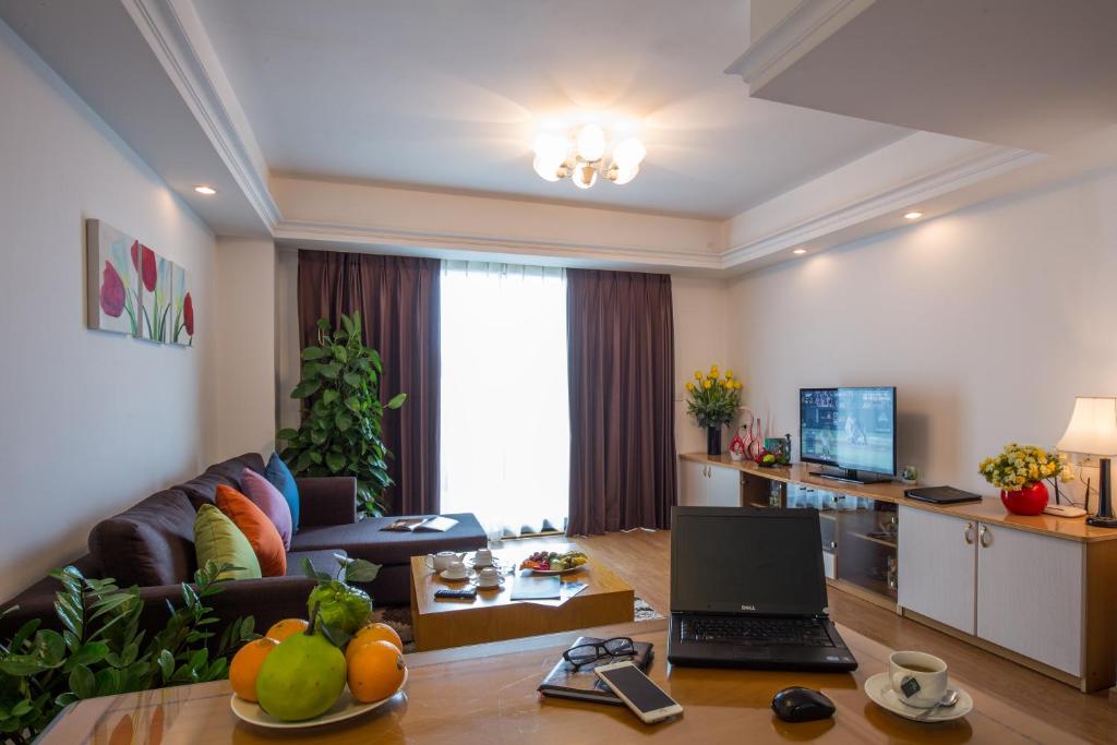 sala de estar con sofá y mesa con ordenador portátil. en Rose Garden Residences en Hanói