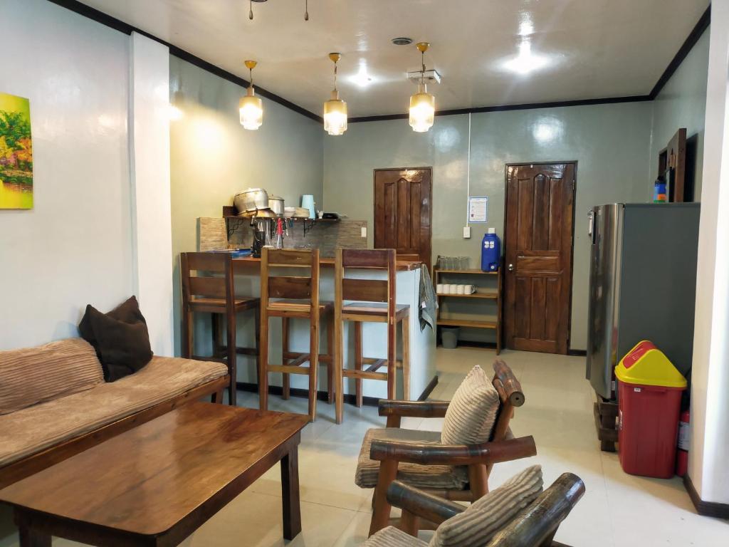 a living room with wooden furniture and a kitchen at Full House in El Nido