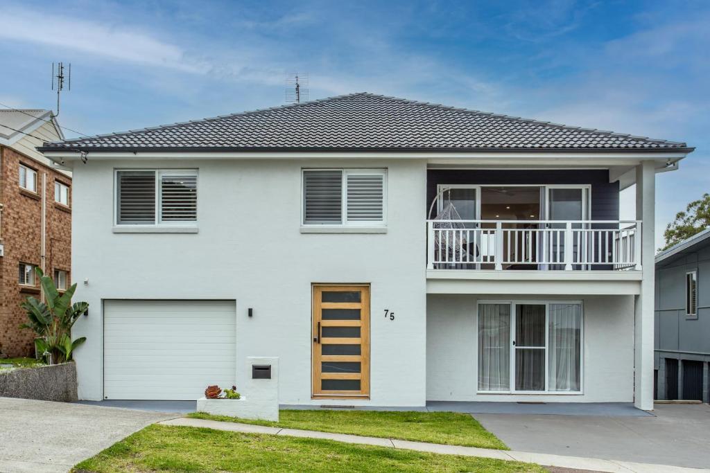 a white house with a balcony and a garage at Cheerful Lakeside House-Minutes away from anywhere in Lake Munmorah