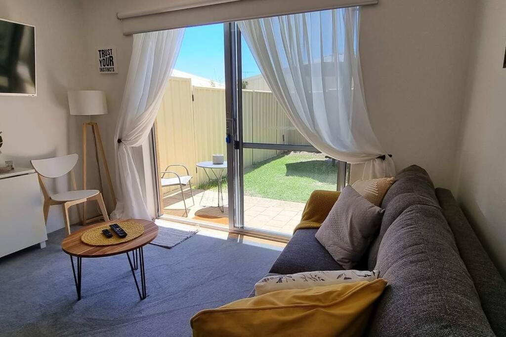 a living room with a couch and a large window at AMAROO -Queen bed - Lounge - Kitchen - Bathroom - Quinns Rocks in Quinns Rocks