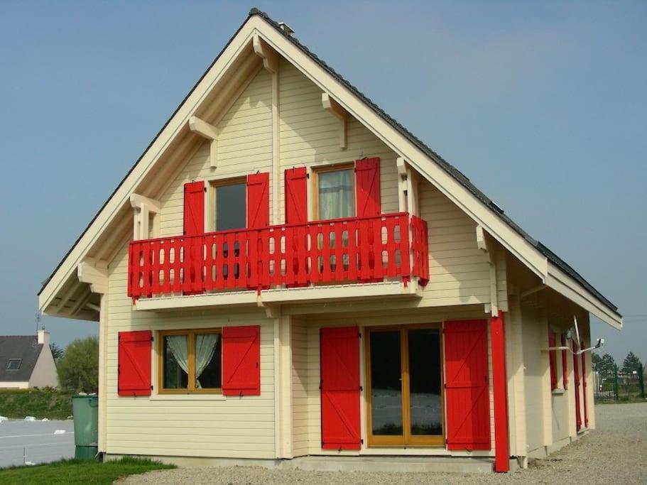 une maison avec un balcon rouge au-dessus dans l'établissement Chalet Familial en Bois à 150 m de la Mer, à Santec
