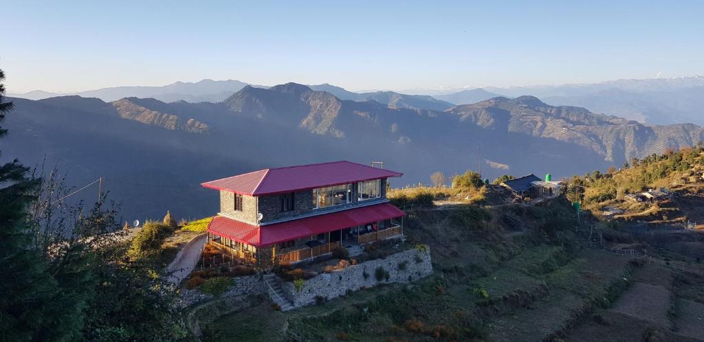 a building with a red roof on a mountain at The Rosly Estate in Kanatal