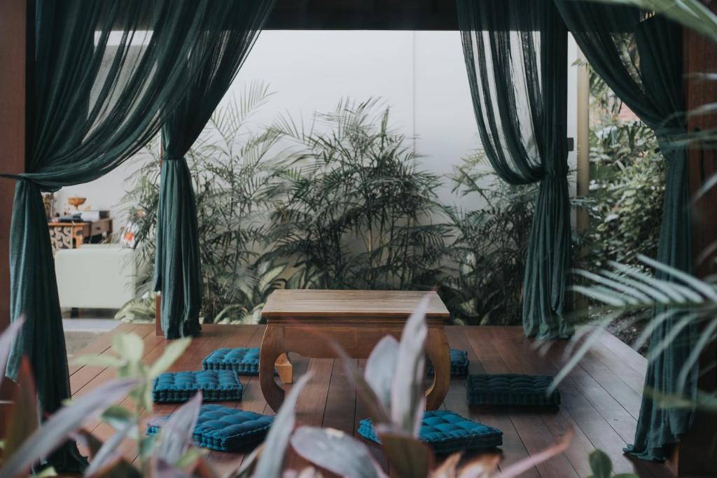 a room with green plants and a table and chairs at Anja Jimbaran in Jimbaran