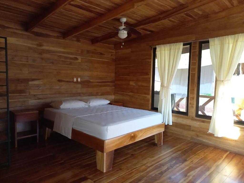 a bedroom with a bed in a room with wooden walls at Cabaña tolle Vista in Savegre