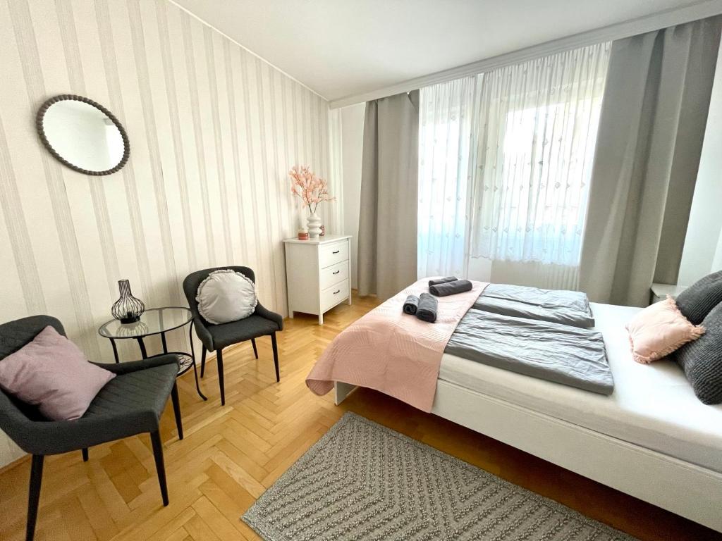 een slaapkamer met een bed, 2 stoelen en een spiegel bij Gozsdu Court Premier Apartment in Boedapest