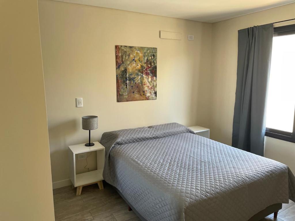 1 dormitorio con 1 cama y una pintura en la pared en Complejo de departamento lencinas en Godoy Cruz
