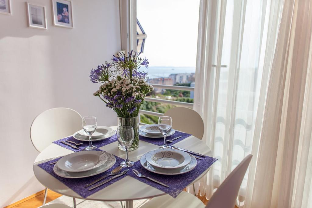 a table with plates and glasses and a vase with flowers at Apartment Skocibusic in Split