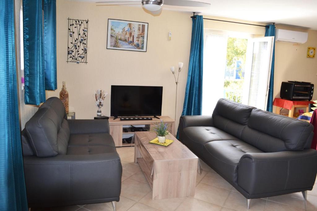 a living room with two leather couches and a television at Résidence Niccola in Vidauban