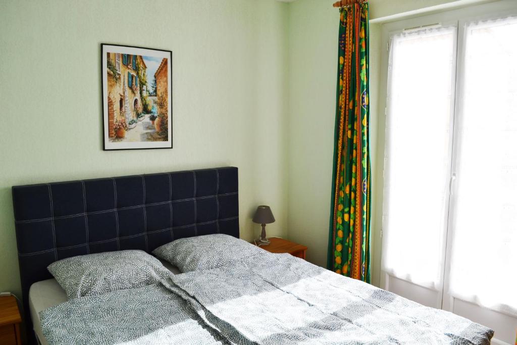 a bedroom with a bed with a blue headboard and a window at Résidence Niccola in Vidauban