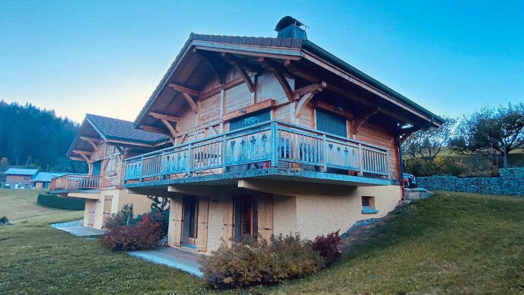 a wooden house with a balcony on the side of it at Le Chalet d'Ulysse in Arâches-la-Frasse