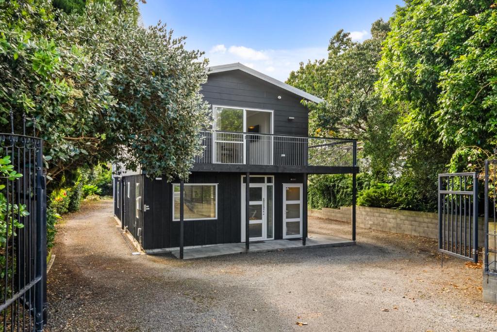 uma casa preta com uma varanda numa entrada em Bold Beauty - Paraparaumu Upstairs Holiday Unit em Paraparaumu
