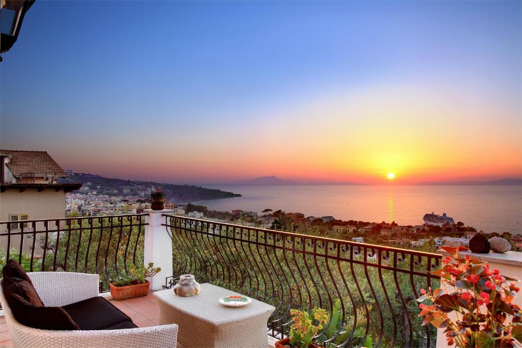 a balcony with a view of the ocean at sunset at M Suites Sorrento in Sorrento