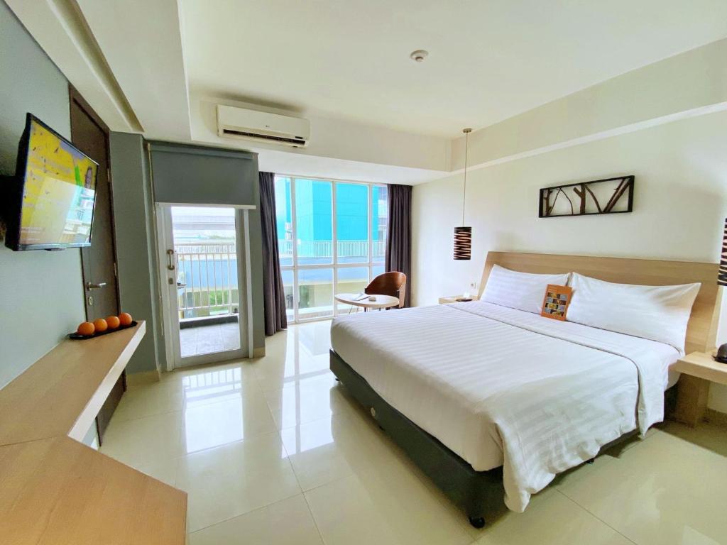 a bedroom with a large white bed and a television at Harper MT Haryono by ASTON in Jakarta