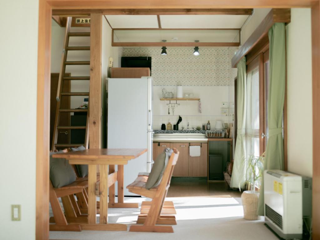 a kitchen with a table and a refrigerator at Cottage Snowhills Hakuba in Hakuba