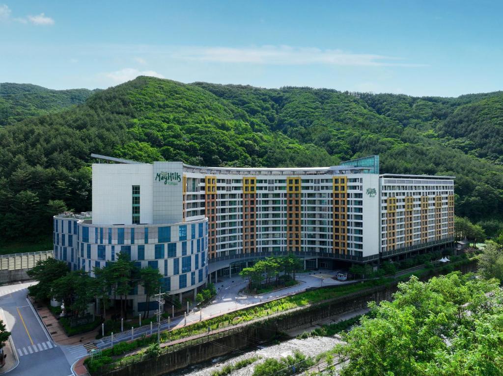 an aerial view of a building with mountains in the background at Jeongseon Mayhills Resort in Jeongseon