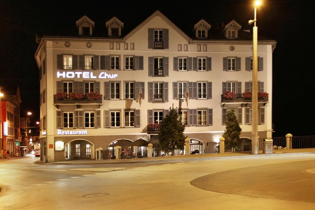 un edificio de hotel con un cartel en él por la noche en HotelChur.ch, en Chur