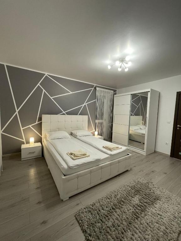 a bedroom with a large white bed and a mirror at Merci Apartament 1,0 in Sibiu