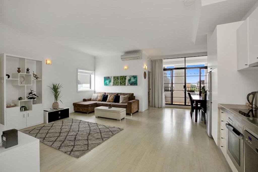 un soggiorno bianco con divano e tavolo di Apartment at Cooper St a Sydney